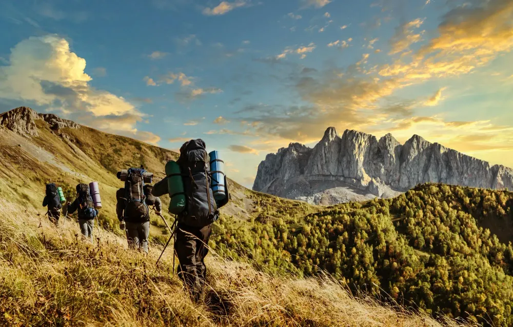 Line of hikers making their way up a mountain path with hiking sticks and backpacks